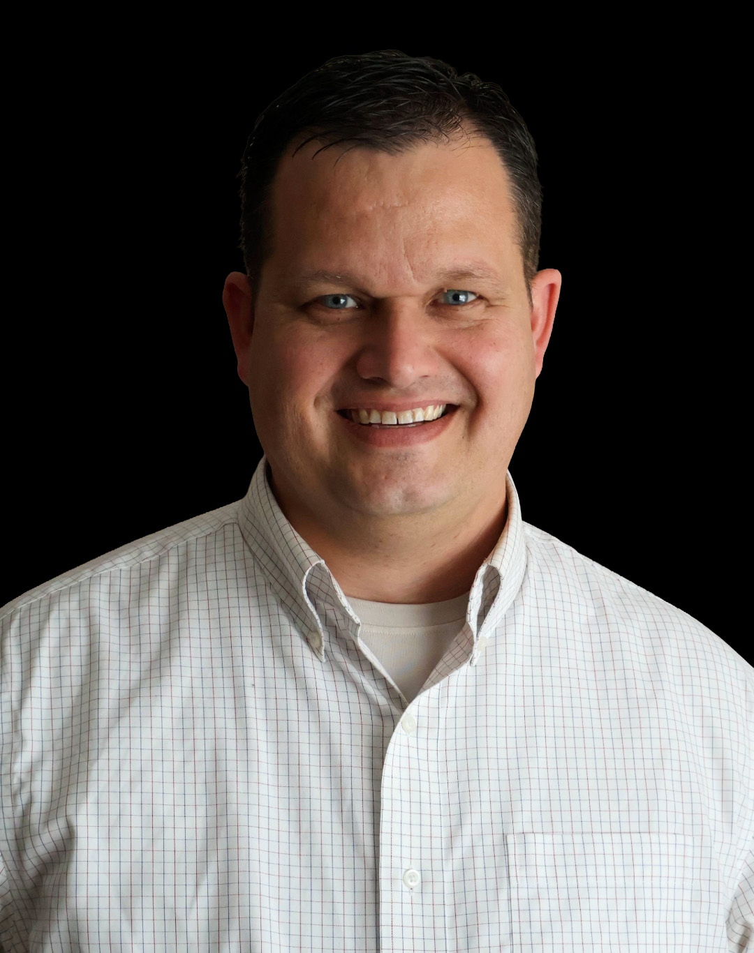 A smiling man in a checkered shirt against a black background, with short dark hair and a warm expression.